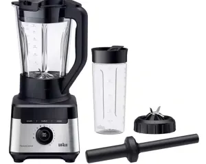 High-power blender with large glass pitcher, travel bottle, blade cap, and tamper accessory set ready for use.