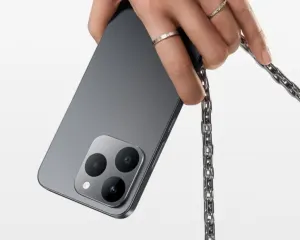 Realme-0005 - مؤسسة العبقري الصغير للتجارة الالكترونية Hand with rings holds a gray smartphone with a silver chain attached to its back.