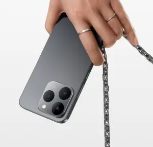Hand with rings holds a gray smartphone with a silver chain attached to its back.
