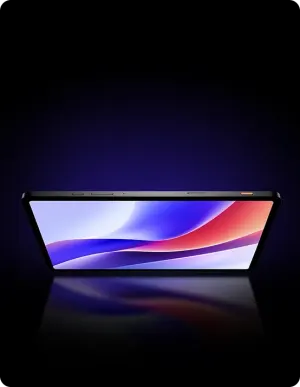 Black tablet on a reflective surface, angled screen showing an abstract blue–purple–red gradient wallpaper against a dark purple background.